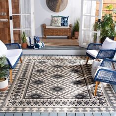 an outdoor area with chairs, rug and potted plants