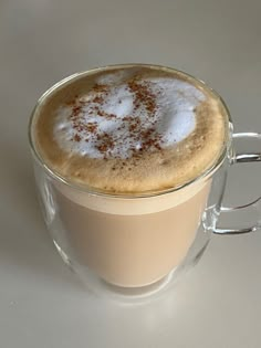 a cappuccino in a glass mug with cinnamon sprinkles on top