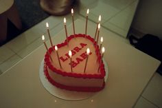 a heart shaped birthday cake with candles on it