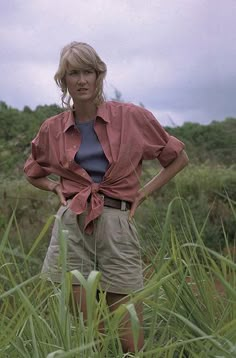 a woman standing in tall grass with her hands on her hips