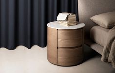 a nightstand with books on it next to a bed