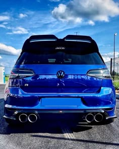 the rear end of a blue car parked in a parking lot