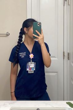 a woman in scrubs taking a selfie with her cell phone