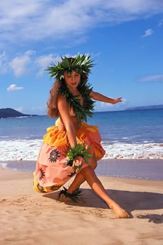 a woman in an orange dress on the beach with a hula skirt and flower wreath around her neck