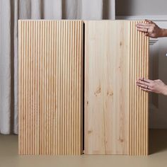 two hands are holding the sides of a wooden cabinet