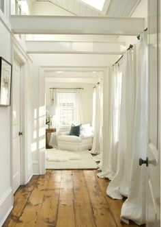 a white room with wood floors and curtains