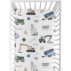 a baby crib with construction vehicles and trucks on the bedding, in white