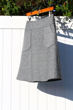 a gray skirt hanging on a white fence