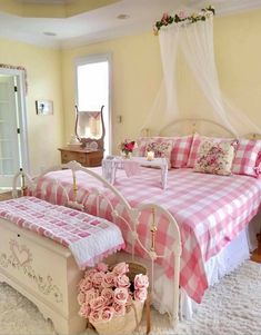 a pink and white bed in a bedroom next to a table with flowers on it