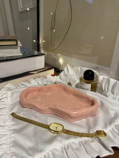 a pink tray sitting on top of a white cloth covered table next to a stack of books