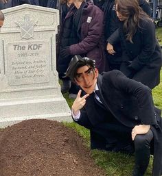 a group of people standing around a man in a suit and tie next to a grave