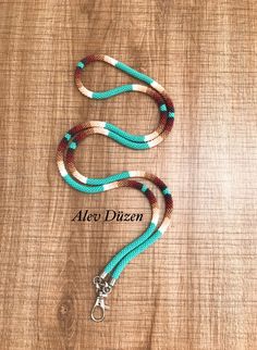 a blue and white rope with silver clasp on a wooden surface that says alex dizzyen