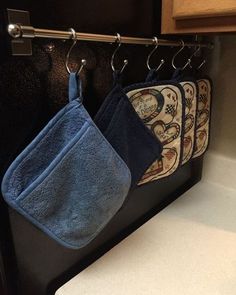 three blue towels hanging from hooks in a kitchen