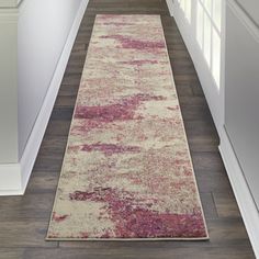 a hallway with white and pink rugs on the floor next to a door way