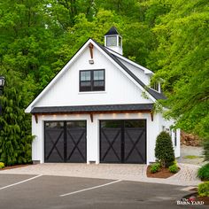 a white barn with two black garage doors