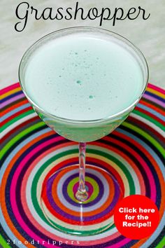 a glass filled with green liquid on top of a colorful plate