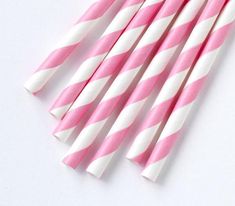 pink and white striped paper straws are lined up on top of each other,