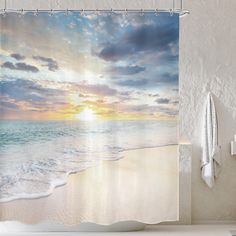 a shower curtain with the sun setting over the ocean and waves coming in from the water