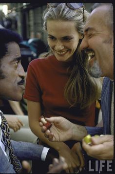 two men and a woman laughing while one holds an apple in her hand as the other looks on