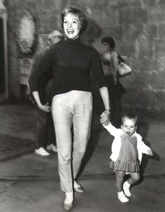 an old black and white photo of a woman holding the hand of a small child