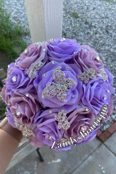 a bridal bouquet with purple flowers and crystal brooches