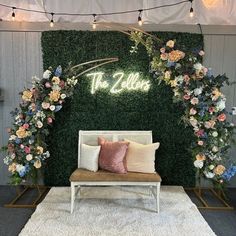 a white couch sitting under a lush green wall with flowers and greenery on it