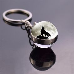 a keychain with a wolf on it and a full moon in the background