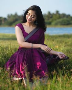 a woman in a purple dress sitting on the grass