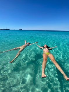 a woman is floating in the ocean with her feet up on a rope while holding onto a tree branch