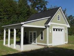 a small garage sits in the middle of a grassy area with trees and bushes behind it