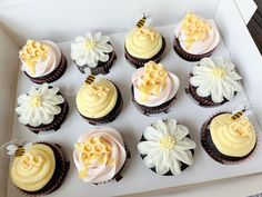 twelve cupcakes with yellow and white frosting in a box on a table