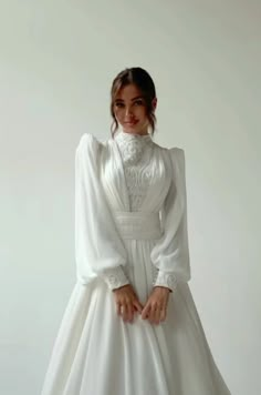 a woman in a white dress posing for the camera with her hands on her hips