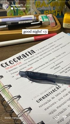 an open notebook sitting on top of a wooden table next to markers and pencils