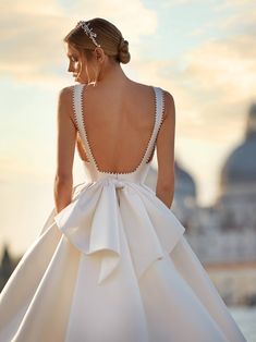 a woman in a white dress with a big bow on her back