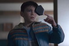 a young boy holding up a black object in front of his face and looking at the camera