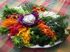 a platter filled with lots of vegetables on top of a checkered table cloth