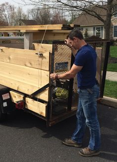 a man standing next to a trailer with a chicken cage in it's back