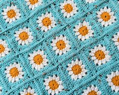 a crocheted blanket with orange and white flowers on it's edges is shown