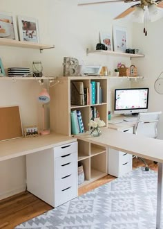 a desk with a computer on top of it in front of a wall mounted fan