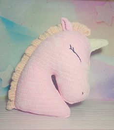 a pink stuffed unicorn laying on top of a table