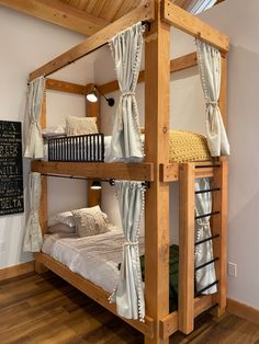 the bunk bed is made from wood and has white curtains on it's sides