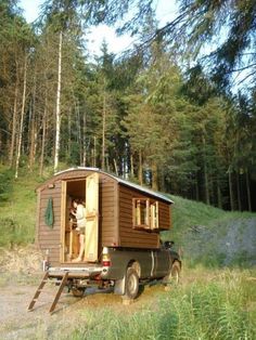 a man standing in the back of a truck with a small cabin on it's flatbed