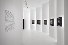 an empty room with white walls and black framed pictures