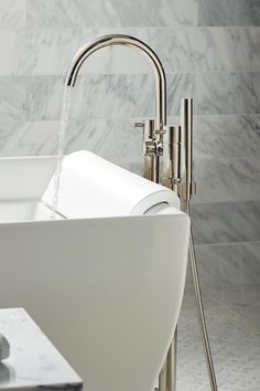 the faucet is running water in the bathtub with marble walls and floor