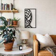 a living room with bookshelves and plants on the wall next to a couch