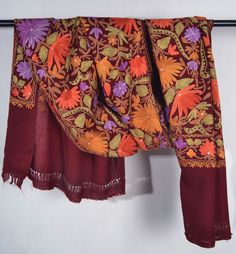 The warm, earthy hue of the scarf is reminiscent of autumn leaves, evoking a cozy feeling perfect for the cooler weather. Intricate floral embroidery in shades of sunset yellow, lavender and orange dance across the fabric, bringing to mind blooming gardens in springtime. The delicate embroidery has taken many hours of skilled artistry, with each individual flower and leaf stitched by hand. Quality : Highest Quality 100% Merino Wool Shawl Size: 30x80 inch or 75x200 cm Origin: Kashmir, INDIA.  The Kashmiri Pashmina Shawl, Lavender And Orange, Sunset Yellow, Handwoven Shawls, Kashmir India, Floral Shawl, Embroidered Scarf, Delicate Embroidery, Cozy Feeling