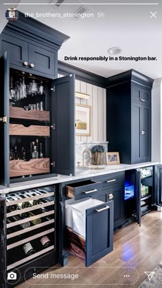 a kitchen with black cabinets and wine racks in the center, along with a white counter top