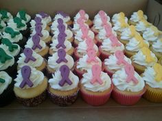 there are many cupcakes in the box with white frosting and purple icing