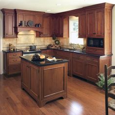 a large kitchen with wooden cabinets and black counter tops, along with an island in the middle