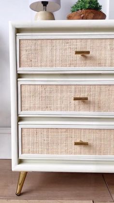 a white dresser with gold handles and wicker baskets on it's bottom drawer